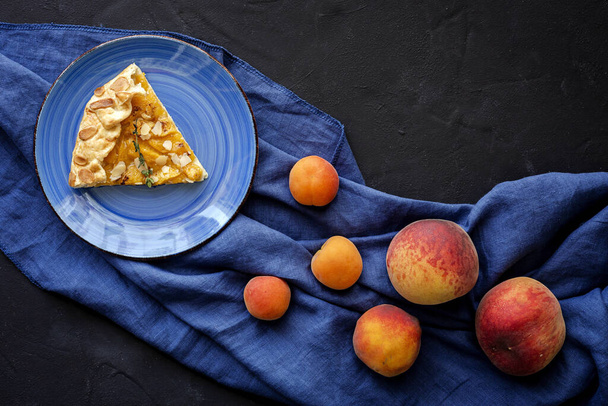 Homemade tart galette with peaches and almonds from above on darkbackground.Flat lay.Top view - Zdjęcie, obraz