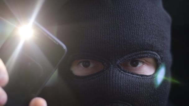 Um atacante com uma lanterna em uma máscara escura procura na sala
 - Filmagem, Vídeo