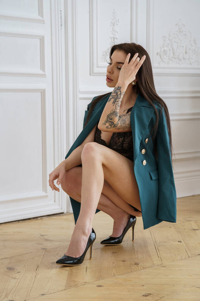 Beautiful brunette model wearing black lingerie, high heels and casual jacket posing at luxury apartments interior  - Fotografie, Obrázek