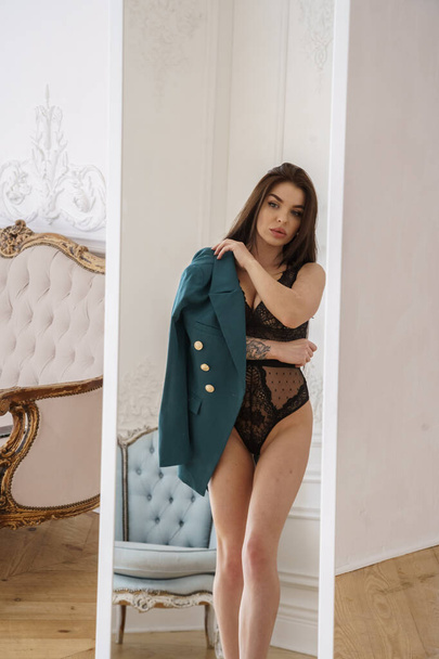Beautiful brunette model wearing black lingerie, high heels and casual jacket posing at luxury apartments interior  - Foto, Bild