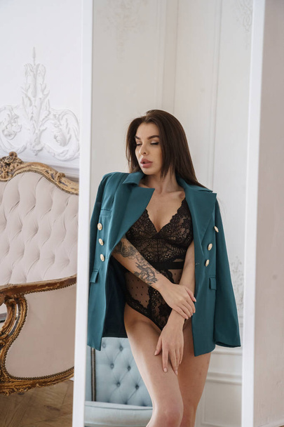 Beautiful brunette model wearing black lingerie, high heels and casual jacket posing at luxury apartments interior  - Fotoğraf, Görsel