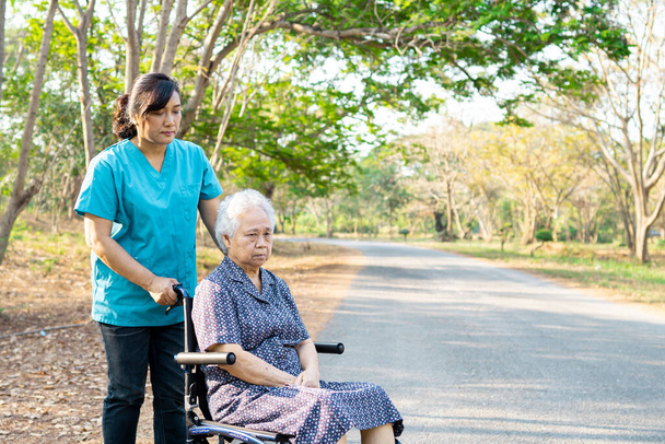 Βοήθεια και φροντίδα των νοσοκόμων Ασιάτισσα ηλικιωμένη ή ηλικιωμένη ηλικιωμένη γυναίκα ασθενής που κάθεται σε αναπηρικό καροτσάκι στο χώρο στάθμευσης στην πτέρυγα του νοσηλευτικού νοσοκομείου: υγιής ισχυρή ιατρική έννοια  - Φωτογραφία, εικόνα