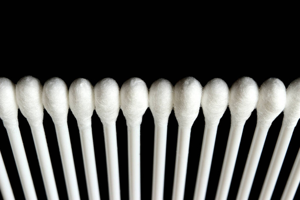 White cotton buds are arranged in an orderly and beautiful way on a black background. - Фото, зображення