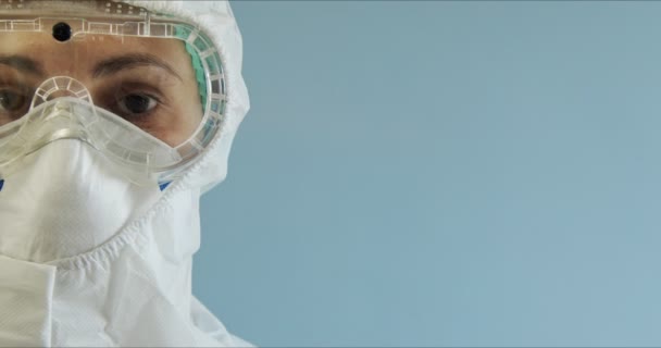 Doctor in protective suit with face mask, eyeglasses and gloves portrait. Nurse in protective suit with face mask, eyeglasses and gloves. Woman wearing protection suite. Copyspace - Filmmaterial, Video