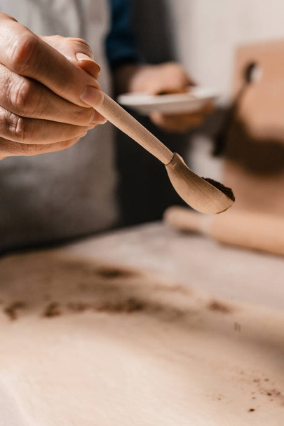 Woman sprinkles a pinch of cinnamon on the dough while baking sweet cookies - Φωτογραφία, εικόνα