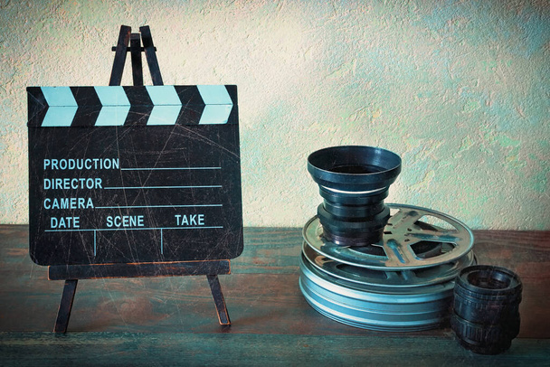 Movies, lenses and clapperboard on a wooden table. Stylized photo. - Photo, Image