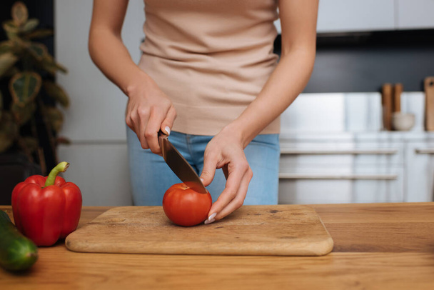 cropped view of young woman cutting fresh tomato on chopping board - Foto, imagen