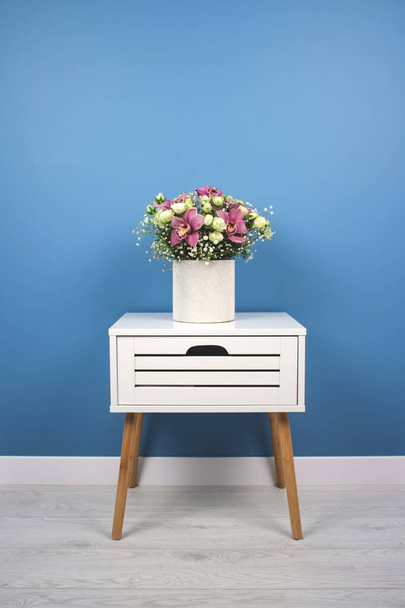Svislé složení květin. Krásná kytice s orchideje a růže na módní modré zdi pozadí v moderním interiéru s kopírovacím prostorem, selektivní zaměření, svatební nebo prázdninový koncept - Fotografie, Obrázek