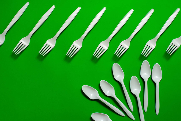 eco-friendly disposable tableware on a green background. isolate. corn starch spoons and forks. biodegradable dishes. natural materials for replacing plastic. place for text - Photo, Image