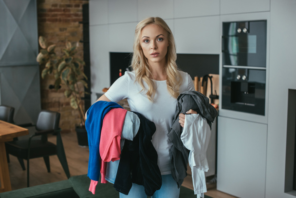 young, blonde housewife looking at camera while holding laundry - Foto, Bild