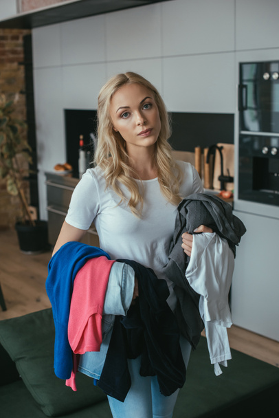 tired housewife looking at camera while holding laundry - Foto, Bild