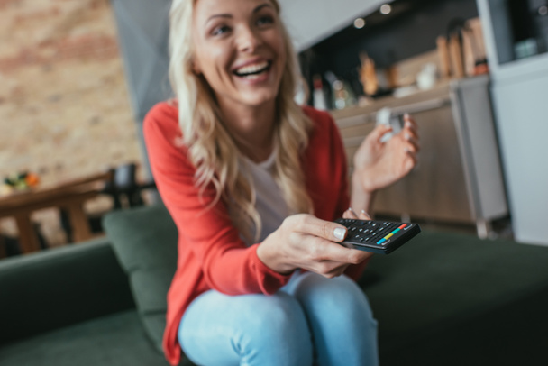 selektivní zaměření veselá žena smějící se při sledování televize doma - Fotografie, Obrázek