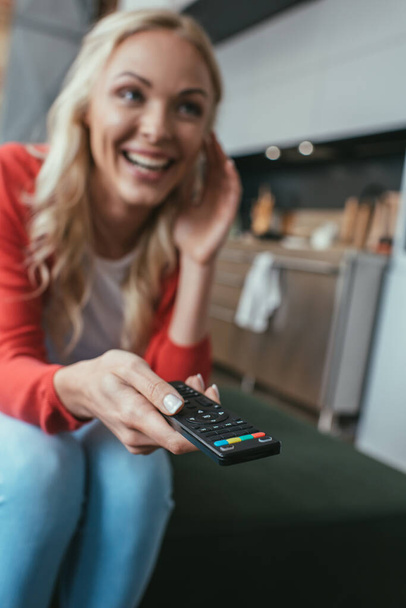 Heyecanlı bir kadının evde televizyon izlerken gülüşünün seçici odağı. - Fotoğraf, Görsel