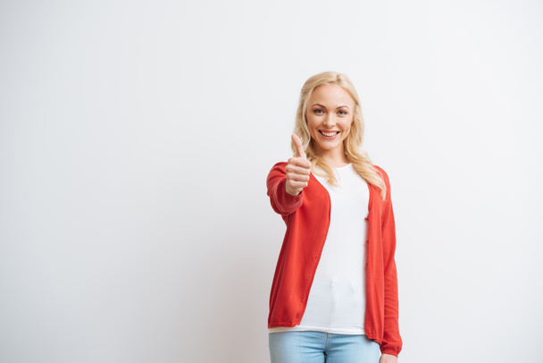 cheerful blonde girl showing thumb up while smiling at camera isolated on white - Photo, Image