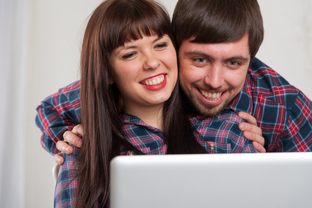 自宅でラップトップを使用して笑っているカップルの肖像画 - 写真・画像