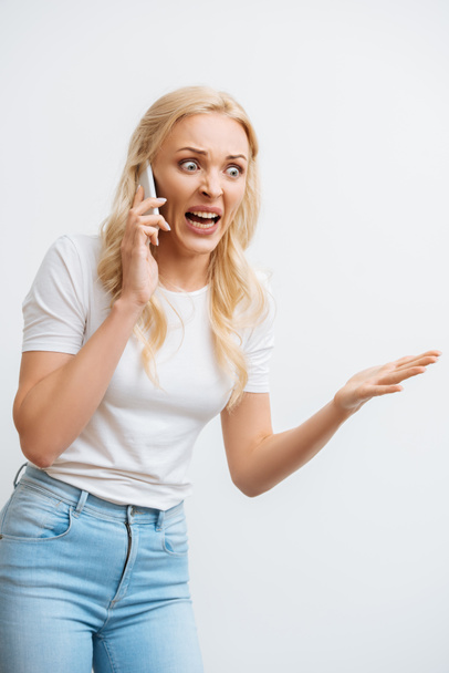 ερεθισμένη γυναίκα φωνάζει στο smartphone, ενώ gesturing με ανοιχτό χέρι απομονώνονται σε λευκό - Φωτογραφία, εικόνα