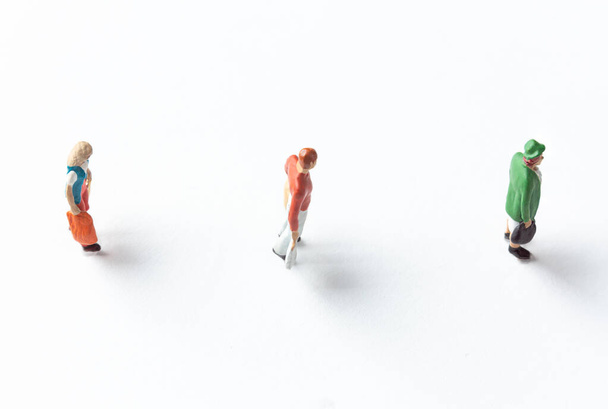 miniatuur mensen figuren op witte achtergrond met veiligheidsafstand gemarkeerd op de grond - Foto, afbeelding