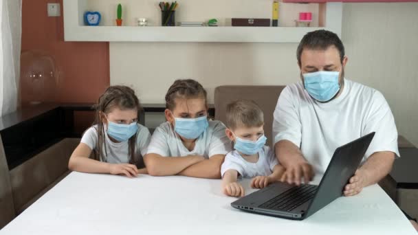 Tata uczy dzieci, jak używać laptopa w domu. Odległość społeczna i izolacja w czasie kwarantanny podczas pandemii COVID-19. - Materiał filmowy, wideo