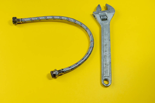 wrench and drain pipe on a yellow background. home repairs for pipes. drain pipe and wrench isolated - Foto, imagen