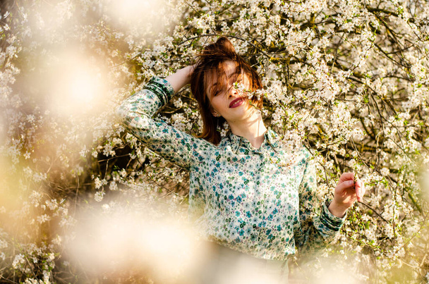 belle femme attrayante posant près de l'arbre à fleurs au jour ensoleillé  - Photo, image