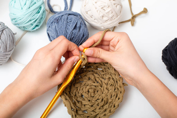 Different colored balls of yarn. Children's hands are crocheted and thread view frome above - 写真・画像