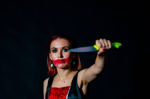 Herrliche rothaarige Frau mit blutigem Messer in der Hand in Nahaufnahme, Halloween-Konzept  - Foto, Bild