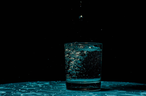 Disparo aislado de agua salpicando de cubos de hielo que se deja caer en un vaso
 - Foto, imagen