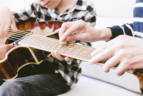 opettaja opettaa nuorta kitarapoikaa. valikoiva kohdentaminen
 - Valokuva, kuva