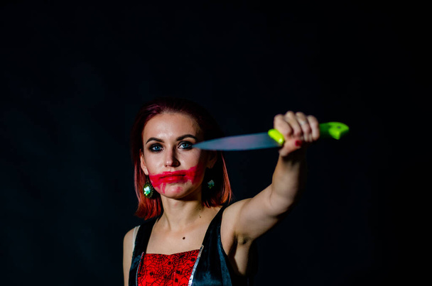 Wspaniała ruda kobieta z zakrwawionym nożem w ręku zbliżenie, koncepcja Halloween  - Zdjęcie, obraz