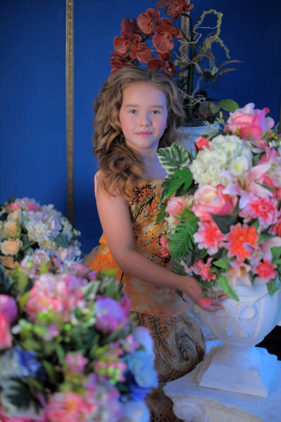 young princess in an orange elegant dress among flowers - Foto, Bild