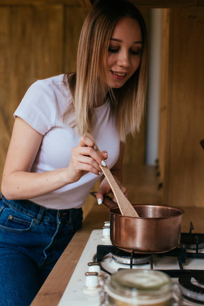 Porträt einer blonden Frau, die in ihrer Küche mit einem Tablet-Computer kocht - Foto, Bild