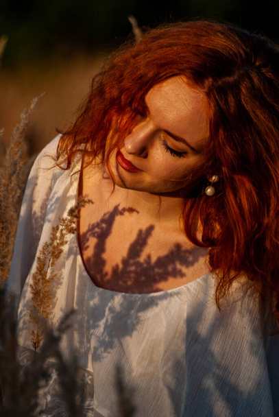 punatukkainen kaunis nainen poseeraa ruohoa niityllä
   - Valokuva, kuva