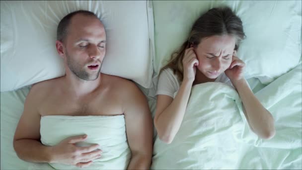 A disgruntled frustrated young woman cant sleep while her boyfriend snores in bed in the bedroom - Záběry, video