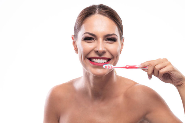Beautiful woman holding a toothbrush and happily smiling  - Foto, imagen