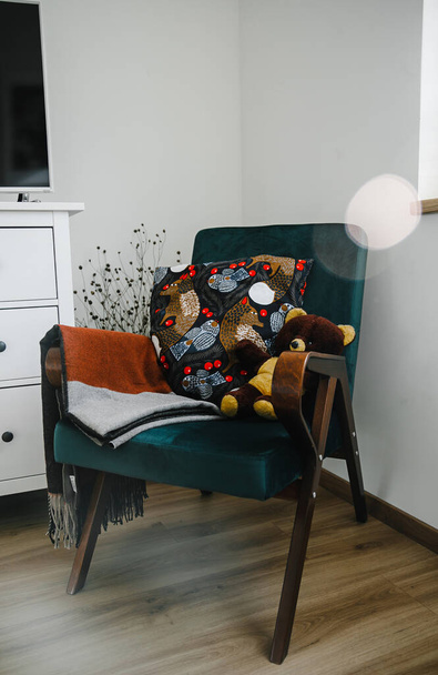 stylish interior - a green velvet chair, a bear and a multi-colored pillow - Zdjęcie, obraz