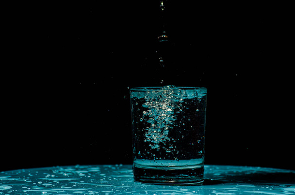 Tiro isolado de água salpicando de cubos de gelo sendo jogado em um copo
 - Foto, Imagem