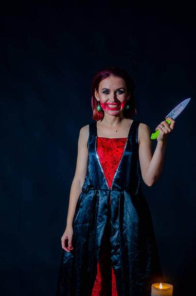 Gorgeous redhead woman with bloody knife in her hand close-up, Halloween concept  - Фото, зображення