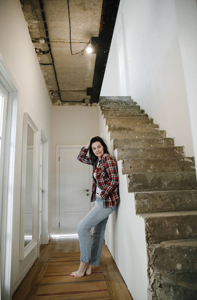 girl in a plaid shirt stands in her house, unfinished repairs - Fotografie, Obrázek