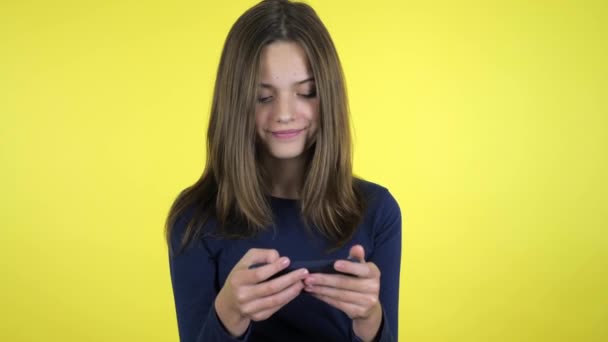Emocional chica adolescente en un suéter juega videojuego en el teléfono inteligente gana y sonríe
 - Imágenes, Vídeo