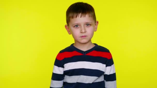 Σοβαρό μικρό παιδί χαμογελά σε κίτρινο φόντο με αντίγραφο χώρο - Πλάνα, βίντεο