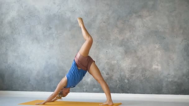 meisje doet yoga in helder studio, voert asana met longitudinale twine in de lucht - Video