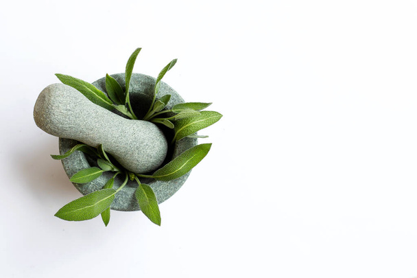 Sage leaves in stone mortar and pestle on white background. Top view - Zdjęcie, obraz