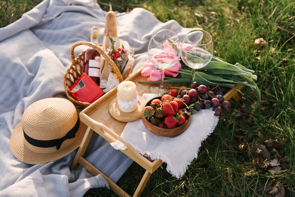 Picnic basket with strawberries, grapes and buns on the green grass in the garden - Φωτογραφία, εικόνα