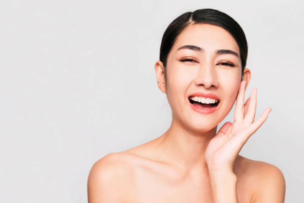 young beautiful asian woman with clean and bright skin, Cosmetic Beauty Concept,hands touch on the cheek, smiling and friendly face isolated on grey background - Valokuva, kuva