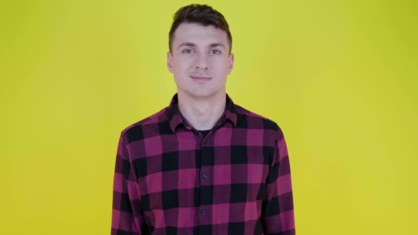 Knappe jongeman flirt met een knipogend oog en glimlacht op een gele achtergrond - Video