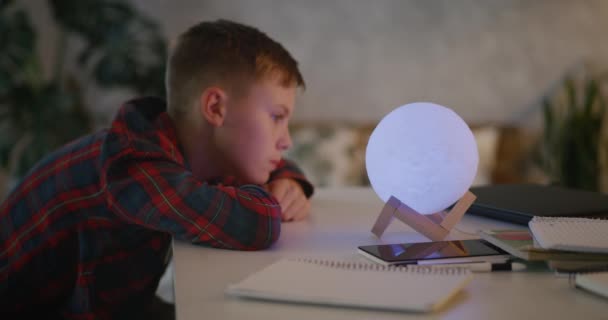 Boy changing color of table lamp - Footage, Video