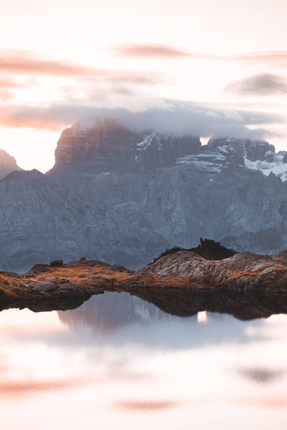 Όμορφο τοπίο με ψηλά βουνά με φωτισμένες κορυφές, πέτρες στη λίμνη βουνό, αντανάκλαση, μπλε του ουρανού και κίτρινο φως του ήλιου κατά την ανατολή. Ο Ιάγος Νίρο. Καταπληκτικό τοπίο στους Δολομίτες - Φωτογραφία, εικόνα