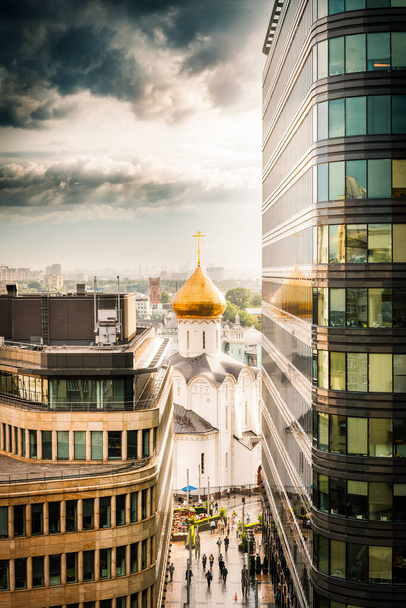 MOSKAU, RUSSLAND - 07. JULE 2016: Blick auf den Tempel des Heiligen Nikolaus in Twerskaja Sastawa (erbaut in den Jahren 1914-1921) zwischen den beiden Bürogebäuden, die sich auf dem Weißen Platz befinden - Foto, Bild