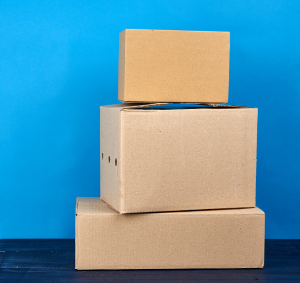 stack of cardboard boxes of brown kraft paper on a blue wooden table, moving concept - Photo, Image
