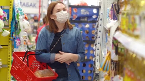 Buyer redhead woman wearing a protective mask with a red basket. - Filmagem, Vídeo